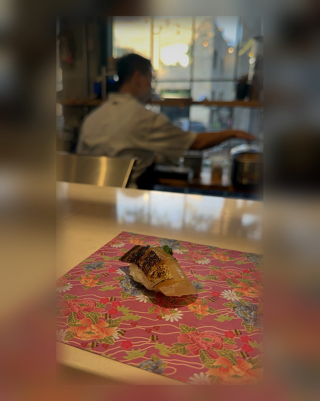 Nigiri maçaricado sobre washi colorido no balcão de omakase do Norigami, em Winter Garden